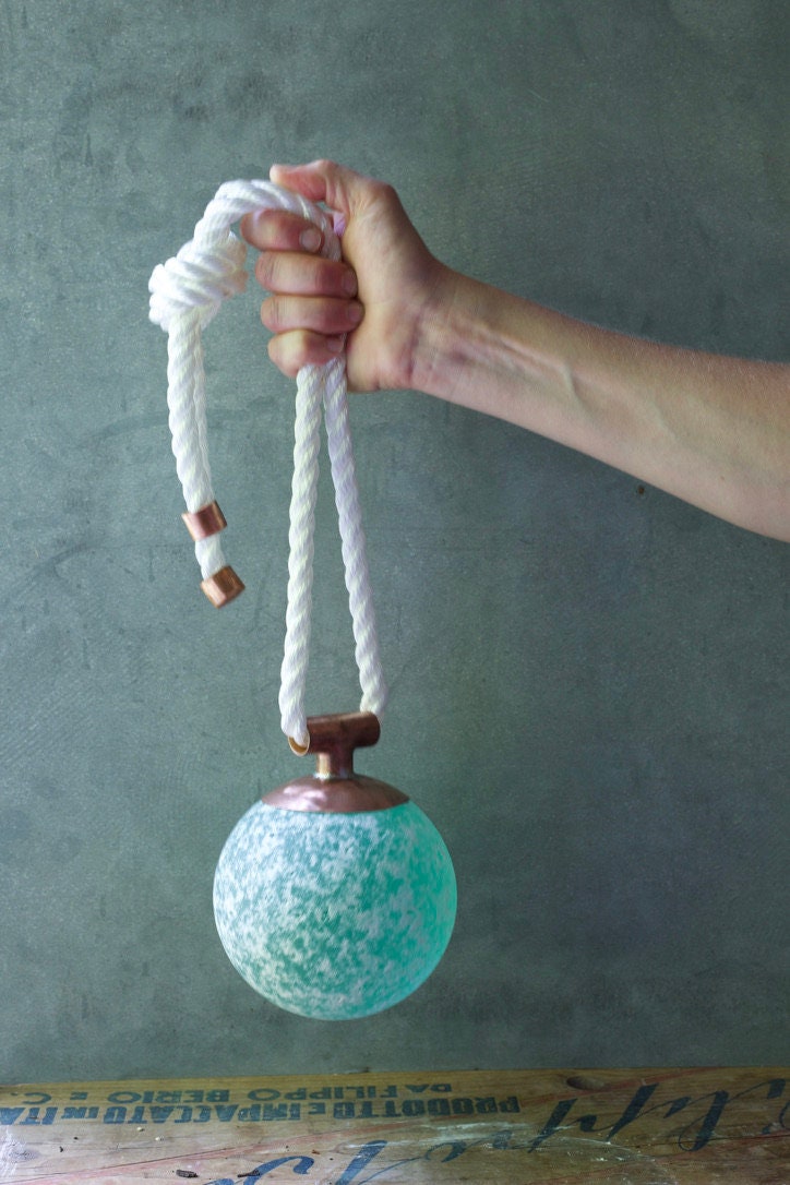 May include: A teal blue glass orb with a white rope handle and copper accents.